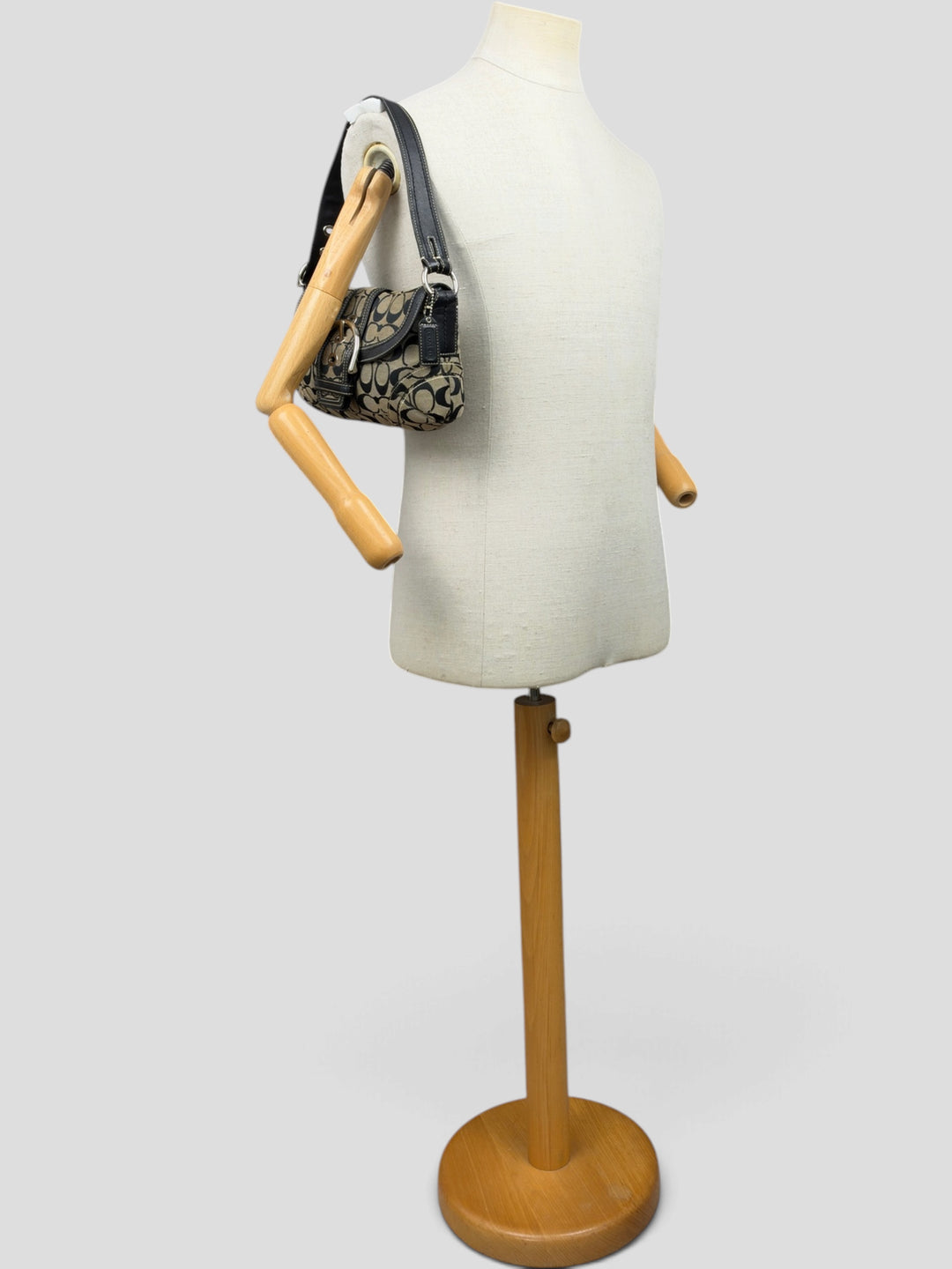 Coach Soho Signature Buckle Flap Baguette Shoulder Bag in Khaki/Schwarz, getragen an der Schneiderpuppe
