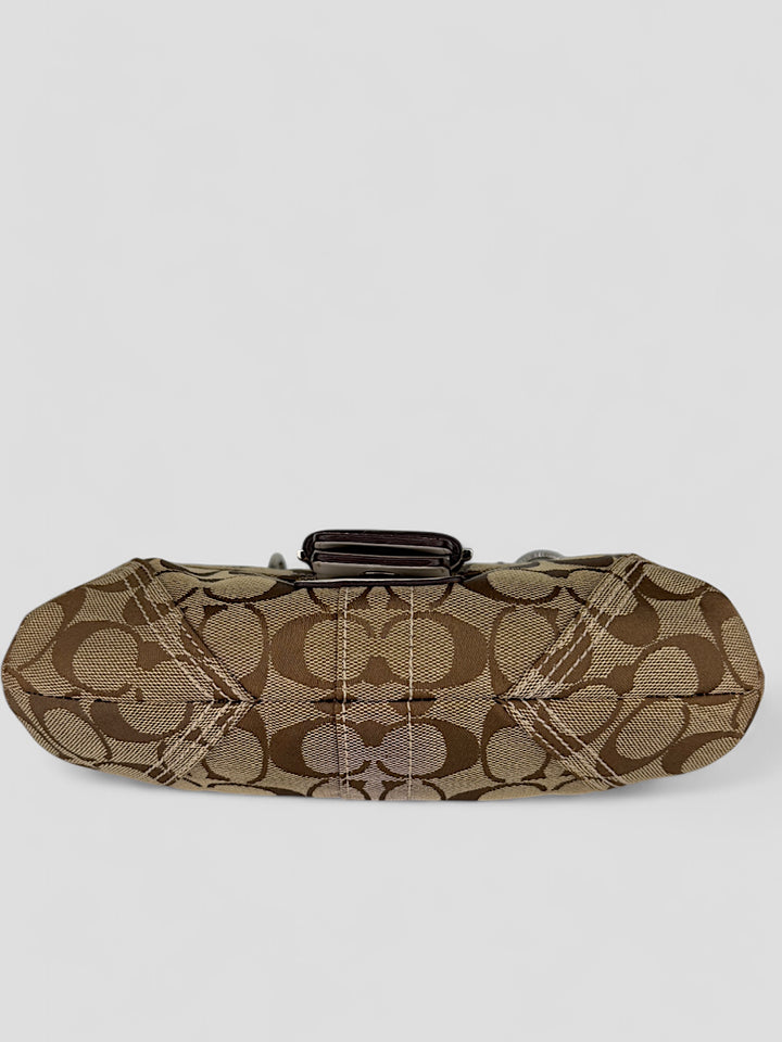 Coach Signature Strapbag mit beigem und braunem Logo-Muster, cremeweißen Lederdetails, silberfarbener Schnalle und geflochtenem Schulterriemen. Kompakt und stilvoll