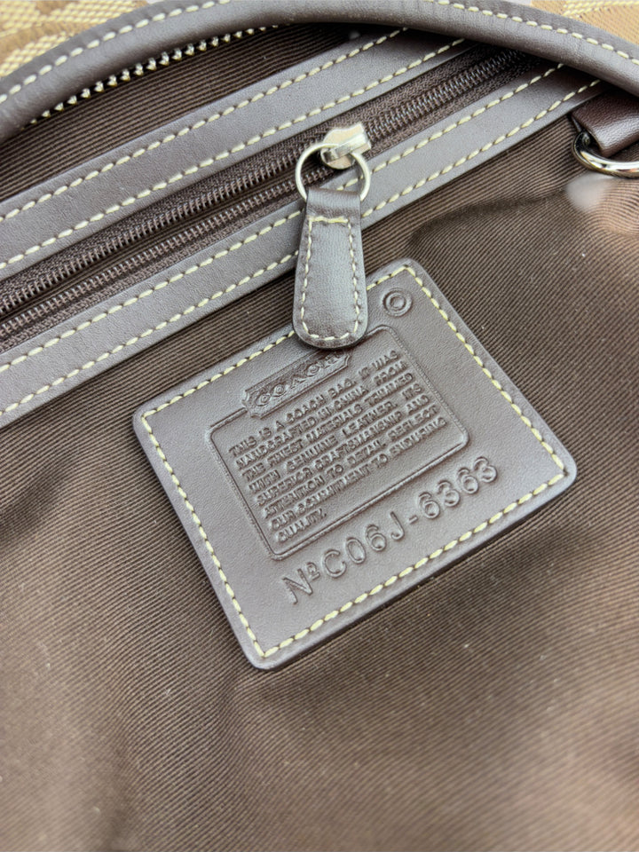 Coach Signature Strapbag mit beigem und braunem Logo-Muster, dunkelbraunen Lederdetails und einer Schnalle auf der Vorderseite. Verstellbare Schulterriemen für maximalen Komfort