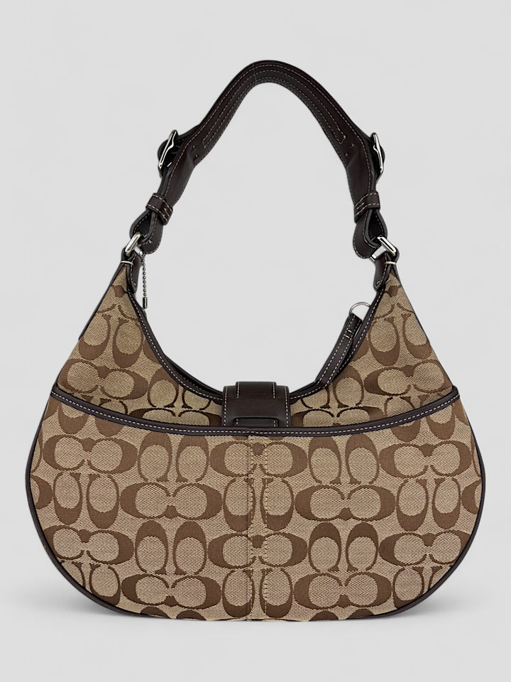 Coach Signature Strapbag mit beigem und braunem Logo-Muster, dunkelbraunen Lederdetails und einer Schnalle auf der Vorderseite. Verstellbare Schulterriemen für maximalen Komfort