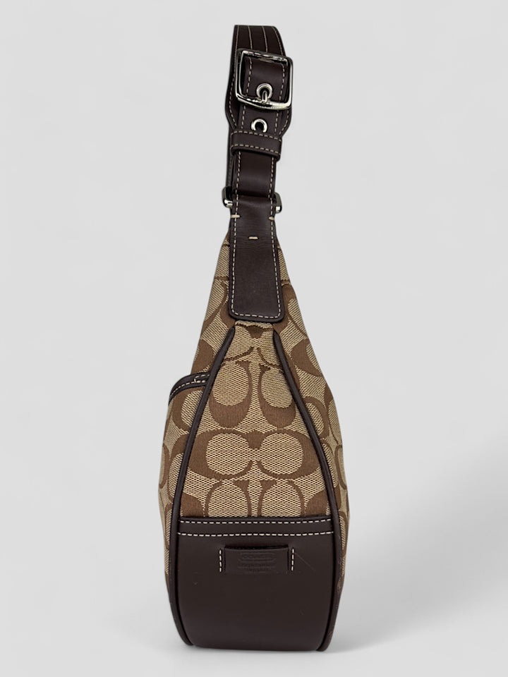 Coach Signature Strapbag mit beigem und braunem Logo-Muster, dunkelbraunen Lederdetails und einer Schnalle auf der Vorderseite. Verstellbare Schulterriemen für maximalen Komfort