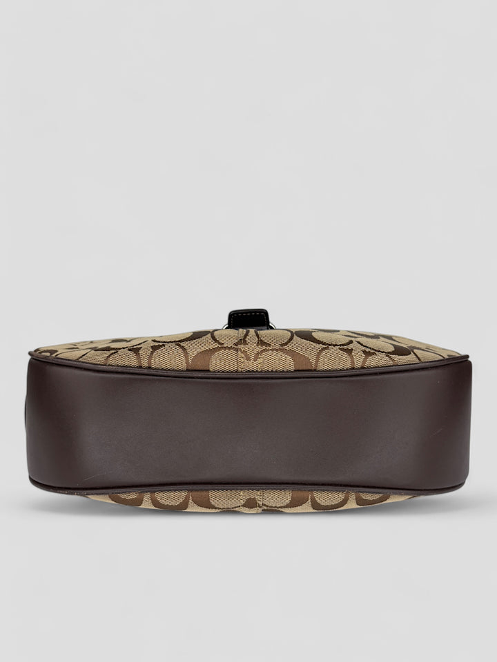 Coach Signature Strapbag mit beigem und braunem Logo-Muster, dunkelbraunen Lederdetails und einer Schnalle auf der Vorderseite. Verstellbare Schulterriemen für maximalen Komfort