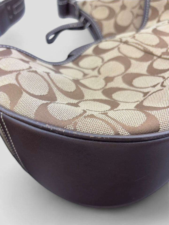 Coach Signature Strapbag mit beigem und braunem Logo-Muster, dunkelbraunen Lederdetails und einer Schnalle auf der Vorderseite. Verstellbare Schulterriemen für maximalen Komfort