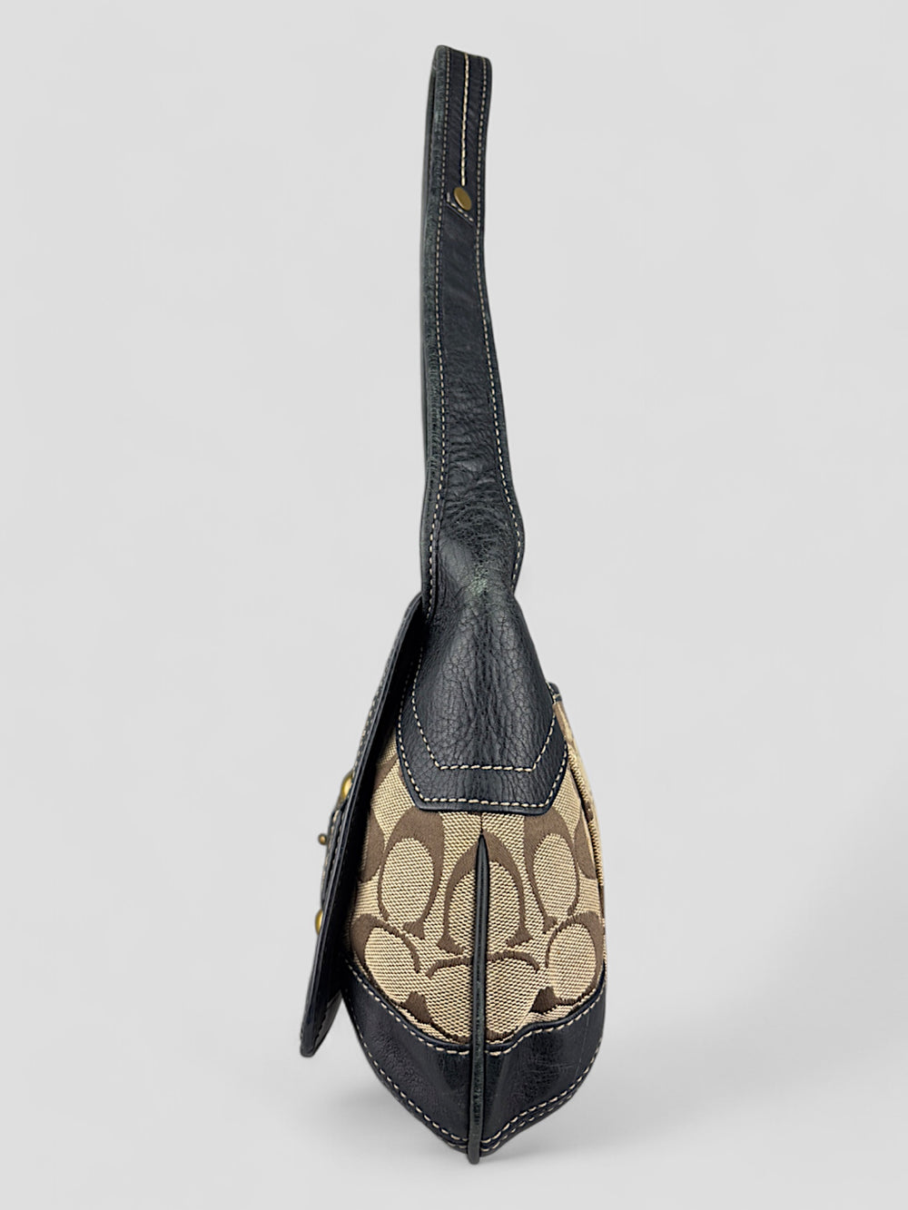 Coach Tasche mit beigem und braunem Logo-Muster, tiefschwarzen Lederdetails, goldfarbenen Beschlägen und einer markanten Schnalle. Stilvoll und luxuriös