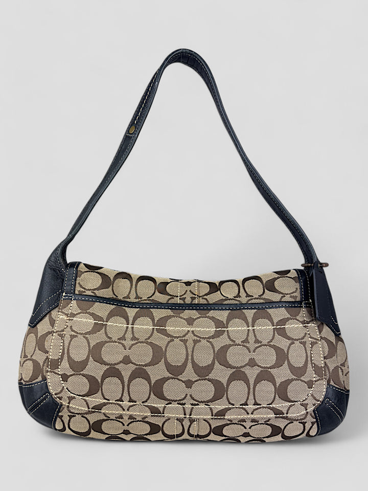 Coach Tasche mit beigem und braunem Logo-Muster, tiefschwarzen Lederdetails, goldfarbenen Beschlägen und einer markanten Schnalle. Stilvoll und luxuriös