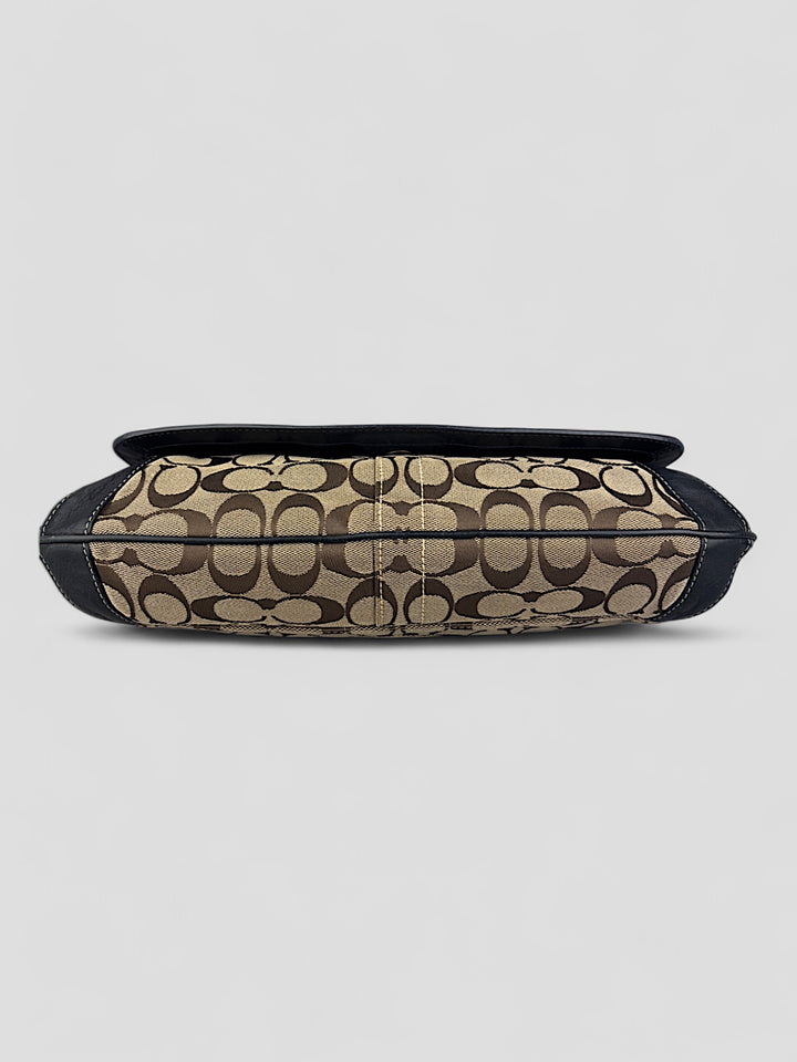 Coach Tasche mit beigem und braunem Logo-Muster, tiefschwarzen Lederdetails, goldfarbenen Beschlägen und einer markanten Schnalle. Stilvoll und luxuriös