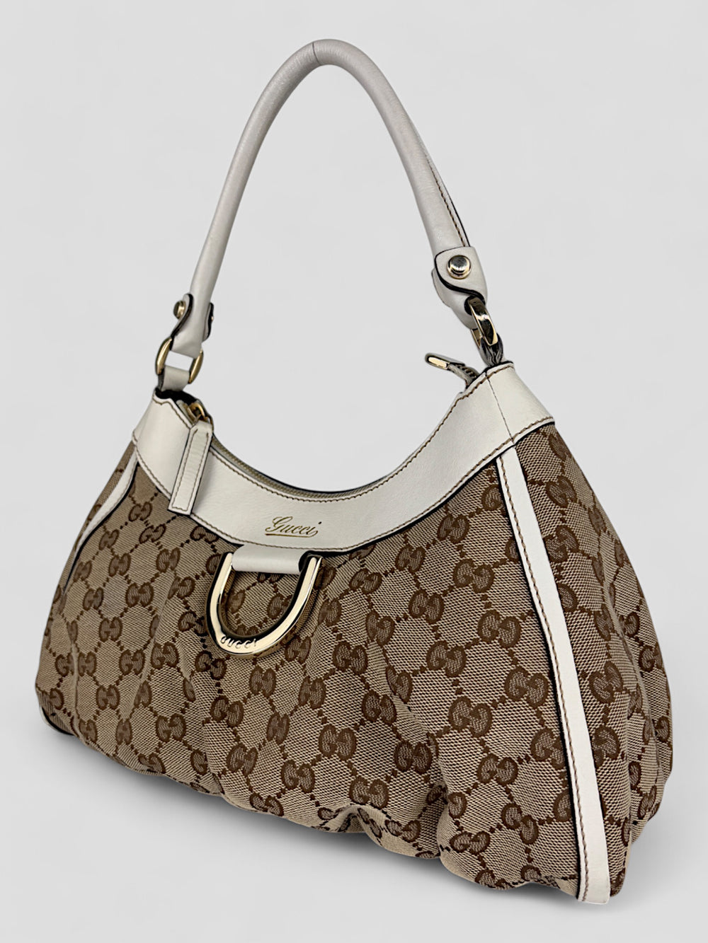 Gucci Abbey D-Ring Tasche aus beigem und braunem GG-Canvas, cremeweißen Lederdetails und ikonischem D-Ring-Element. Kompakt und stilvoll