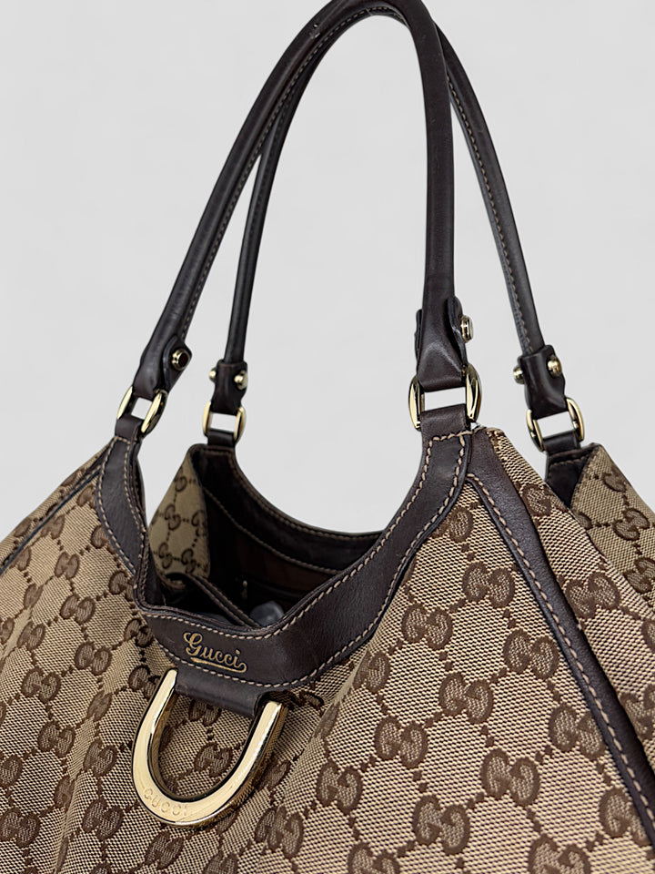 Gucci D-Ring Shoulderbag aus braunem GG-Canvas mit dunkelbraunen Lederdetails, goldfarbenem D-Ring und großzügigem Innenraum. Luxuriös und vielseitig