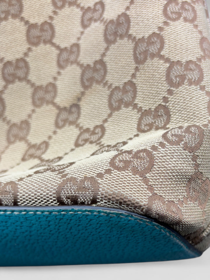 Gucci Hobo Tasche aus beigem Canvas mit GG-Muster, akzentuiert durch türkisfarbene Lederdetails und silberfarbene Metall-Elemente. Stilvoll und modern