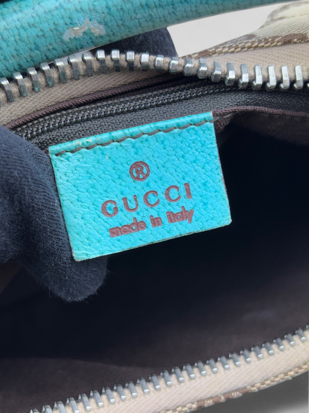 Gucci Hobo Tasche aus beigem Canvas mit GG-Muster, akzentuiert durch türkisfarbene Lederdetails und silberfarbene Metall-Elemente. Stilvoll und modern