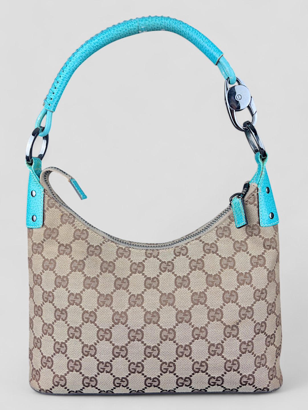 Gucci Hobo Tasche aus beigem Canvas mit GG-Muster, akzentuiert durch türkisfarbene Lederdetails und silberfarbene Metall-Elemente. Stilvoll und modern
