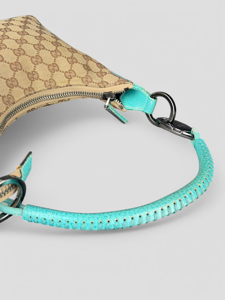 Gucci Hobo Tasche aus beigem Canvas mit GG-Muster, akzentuiert durch türkisfarbene Lederdetails und silberfarbene Metall-Elemente. Stilvoll und modern