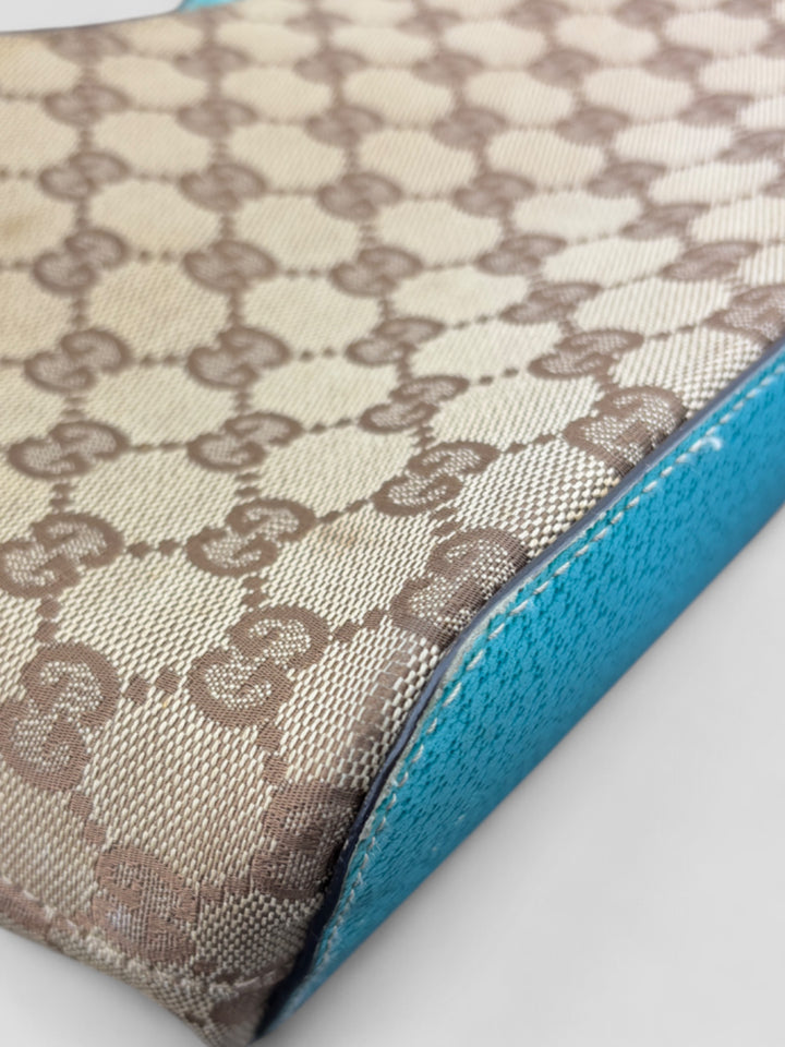 Gucci Hobo Tasche aus beigem Canvas mit GG-Muster, akzentuiert durch türkisfarbene Lederdetails und silberfarbene Metall-Elemente. Stilvoll und modern