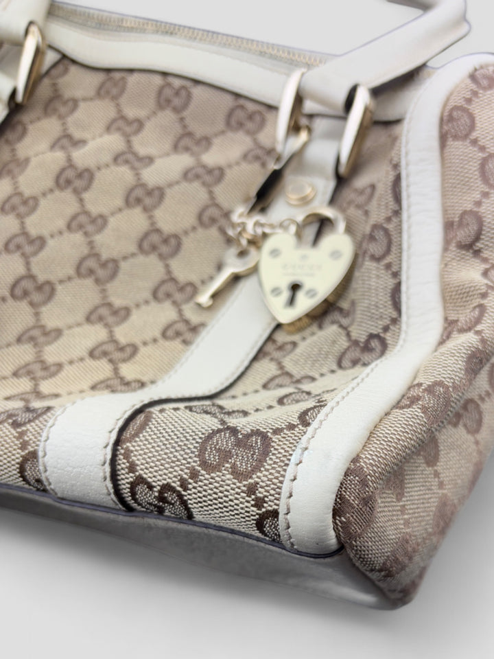 Gucci Schultertasche mit ikonischem Monogramm, weißen Lederdetails und Herzanhänger