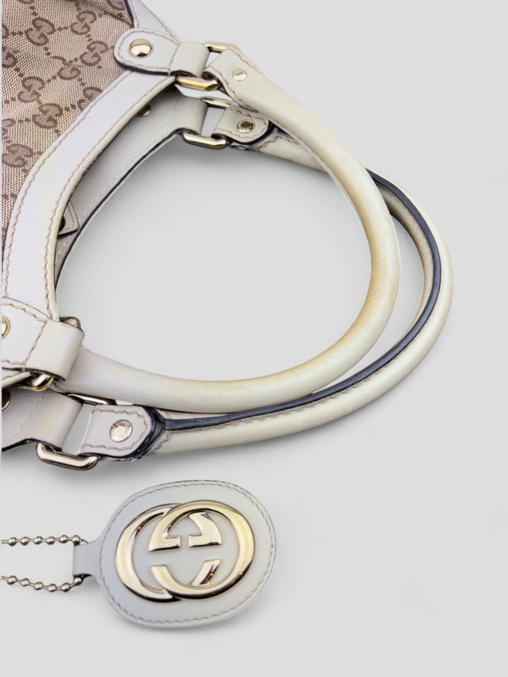 Gucci Sukey Tasche aus cremefarbenem GG-Canvas, ergänzt durch hochwertige Lederdetails und einen abnehmbaren Gucci-Anhänger
