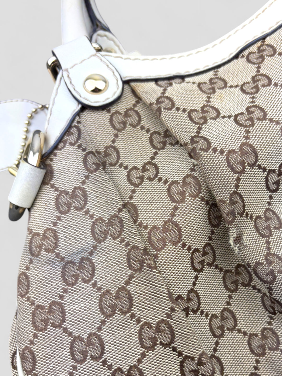 Gucci Sukey Tasche aus cremefarbenem GG-Canvas, ergänzt durch hochwertige Lederdetails und einen abnehmbaren Gucci-Anhänger