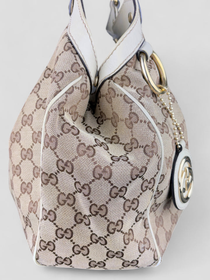 Gucci Sukey Tasche aus cremefarbenem GG-Canvas, ergänzt durch hochwertige Lederdetails und einen abnehmbaren Gucci-Anhänger