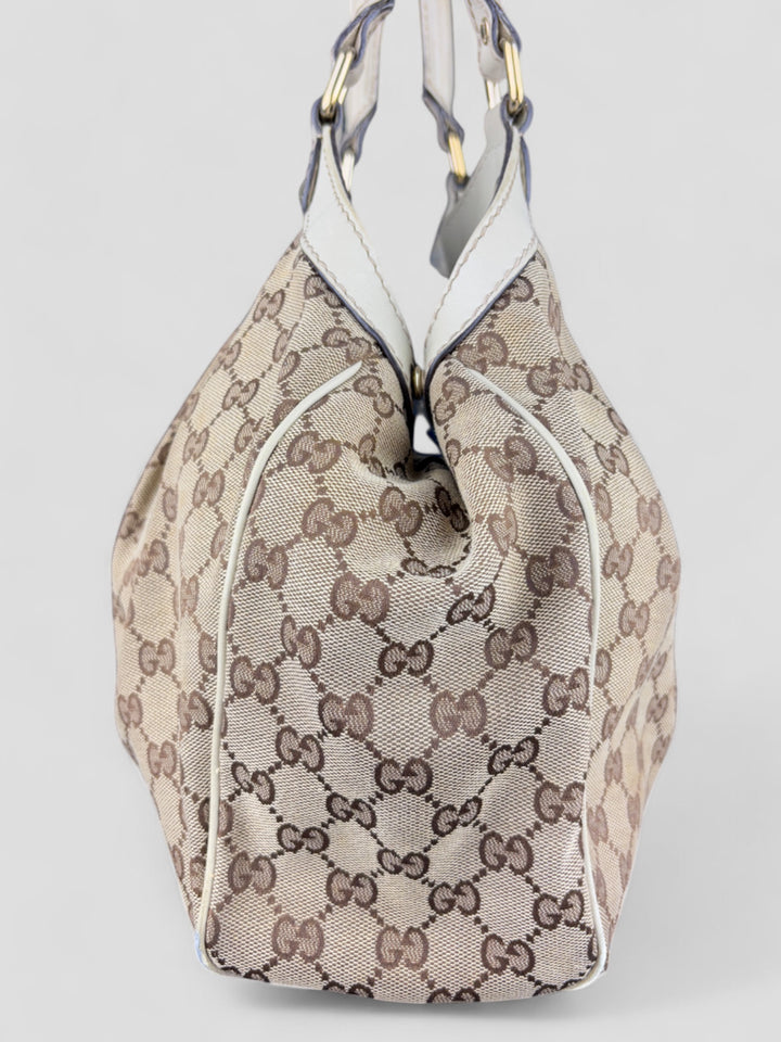 Gucci Sukey Tasche aus cremefarbenem GG-Canvas, ergänzt durch hochwertige Lederdetails und einen abnehmbaren Gucci-Anhänger