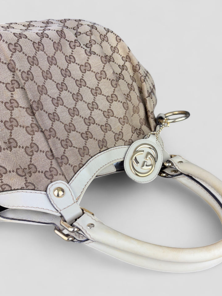 Gucci Sukey Tasche aus cremefarbenem GG-Canvas, ergänzt durch hochwertige Lederdetails und einen abnehmbaren Gucci-Anhänger