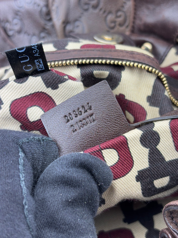 Gucci Sukey Tasche aus schokoladenbraunem Leder mit dezent eingeprägtem GG-Muster, goldfarbenen Nieten und raffiniertem Design. Elegant und geräumig