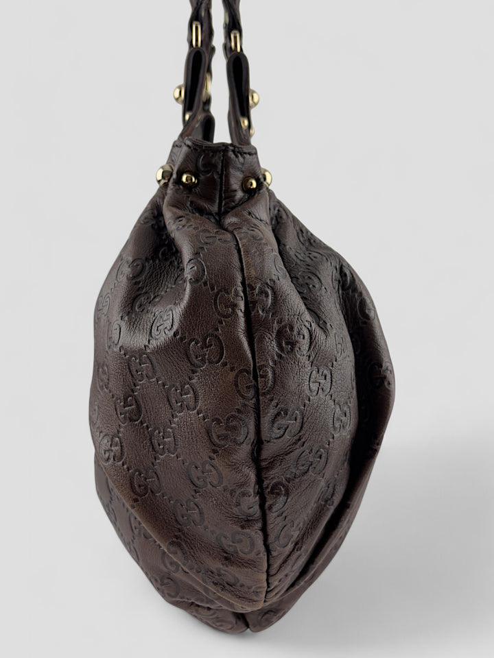 Gucci Sukey Tasche aus schokoladenbraunem Leder mit dezent eingeprägtem GG-Muster, goldfarbenen Nieten und raffiniertem Design. Elegant und geräumig