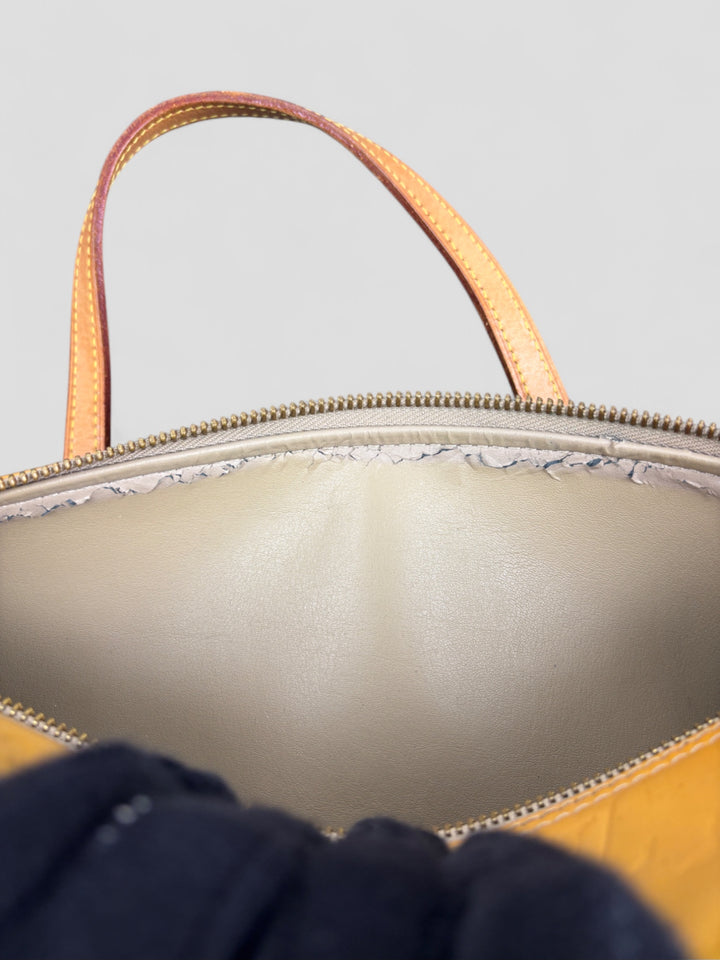 Louis Vuitton Papillon Tasche aus gelbem Lackleder mit glänzendem Finish, goldfarbenen Beschlägen und einer klassischen zylindrischen Form. Stilvoll und auffällig
