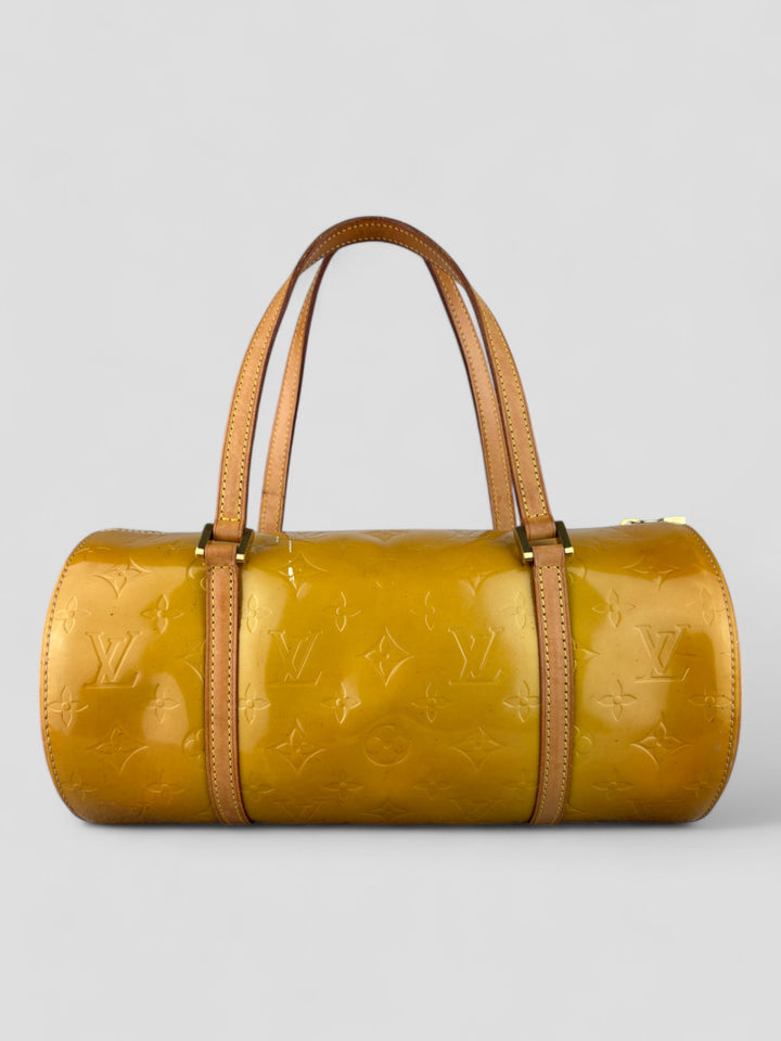 Louis Vuitton Papillon Tasche aus gelbem Lackleder mit glänzendem Finish, goldfarbenen Beschlägen und einer klassischen zylindrischen Form. Stilvoll und auffällig
