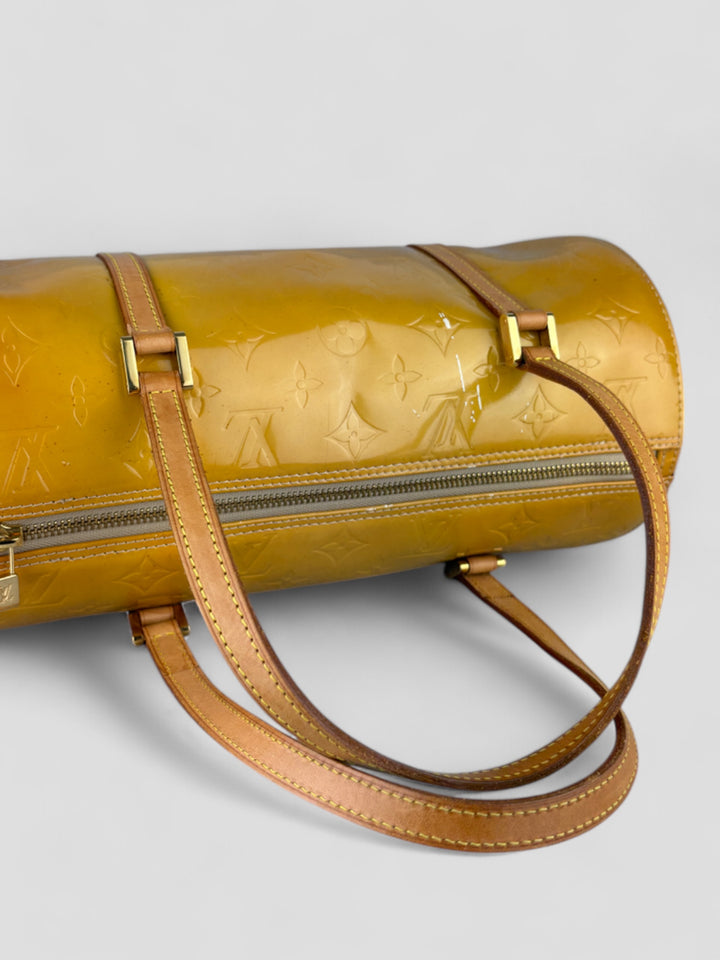 Louis Vuitton Papillon Tasche aus gelbem Lackleder mit glänzendem Finish, goldfarbenen Beschlägen und einer klassischen zylindrischen Form. Stilvoll und auffällig