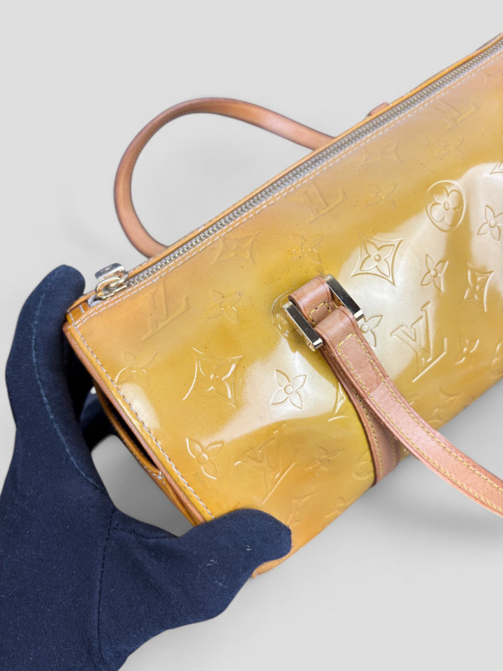 Louis Vuitton Papillon Tasche aus gelbem Lackleder mit glänzendem Finish, goldfarbenen Beschlägen und einer klassischen zylindrischen Form. Stilvoll und auffällig