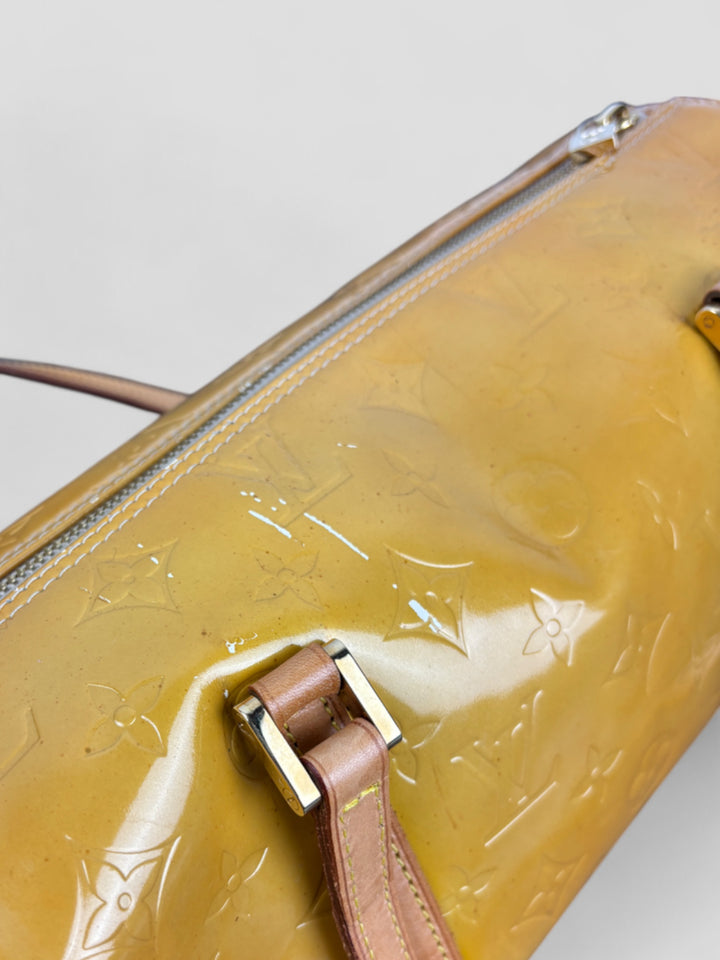 Louis Vuitton Papillon Tasche aus gelbem Lackleder mit glänzendem Finish, goldfarbenen Beschlägen und einer klassischen zylindrischen Form. Stilvoll und auffällig