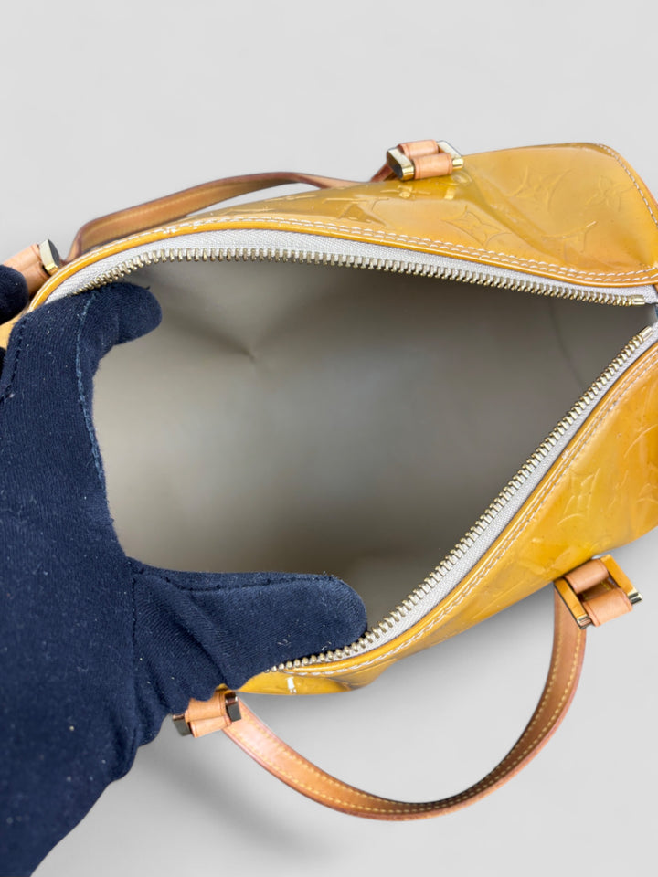 Louis Vuitton Papillon Tasche aus gelbem Lackleder mit glänzendem Finish, goldfarbenen Beschlägen und einer klassischen zylindrischen Form. Stilvoll und auffällig