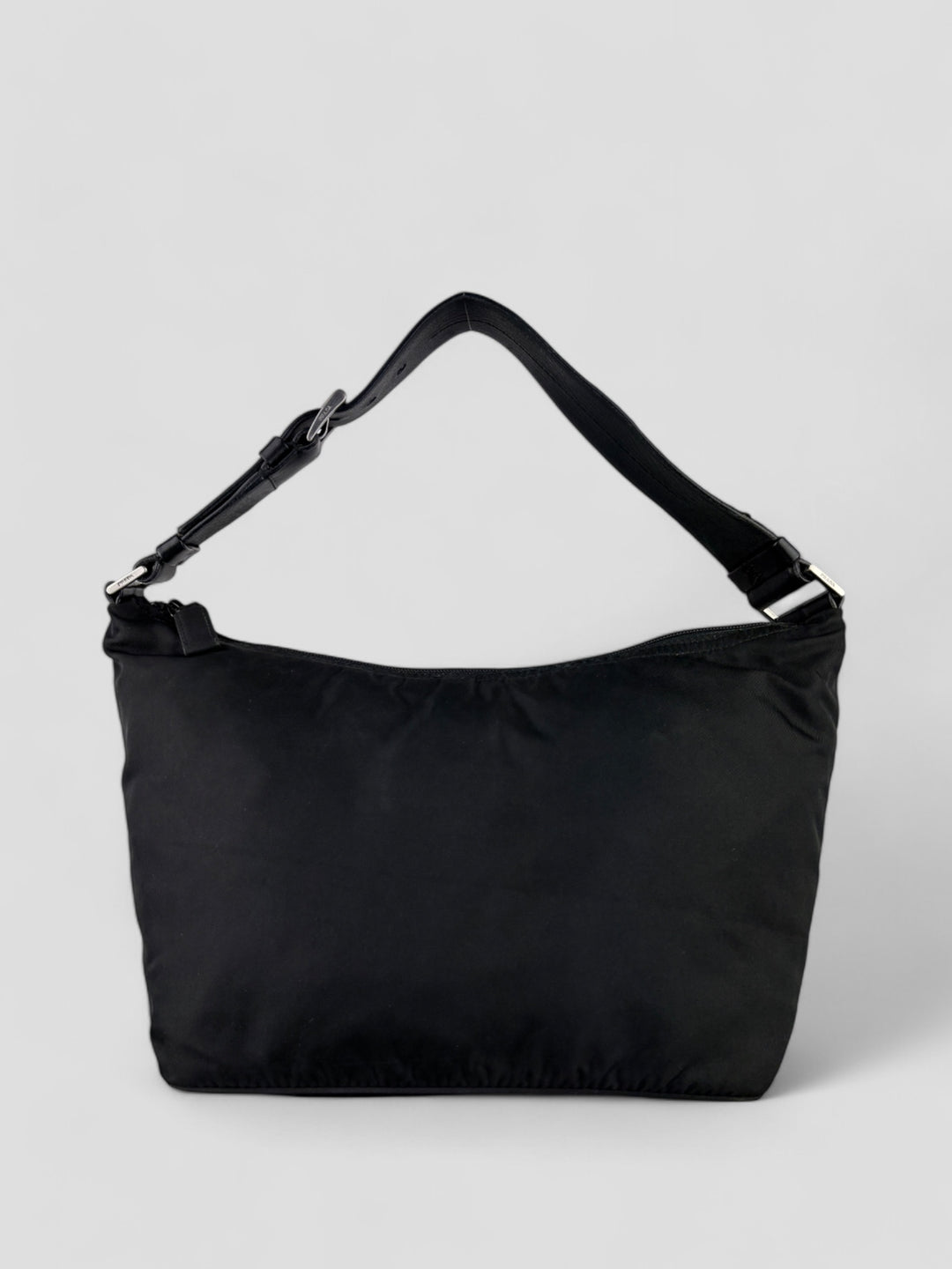 Prada Banana Schultertasche aus schwarzem Nylon mit verstellbarem Schulterriemen und klassischem Prada-Dreiecks-Logoaufnäher. Schlicht, praktisch und elegant.


