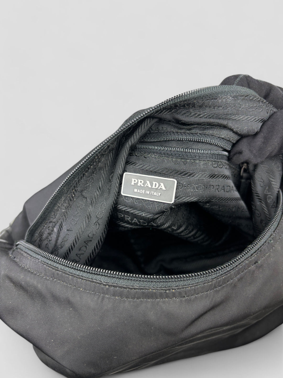 Prada Banana Schultertasche aus schwarzem Nylon mit verstellbarem Schulterriemen und klassischem Prada-Dreiecks-Logoaufnäher. Schlicht, praktisch und elegant