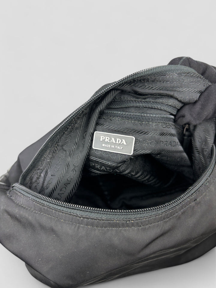 Prada Banana Schultertasche aus schwarzem Nylon mit verstellbarem Schulterriemen und klassischem Prada-Dreiecks-Logoaufnäher. Schlicht, praktisch und elegant