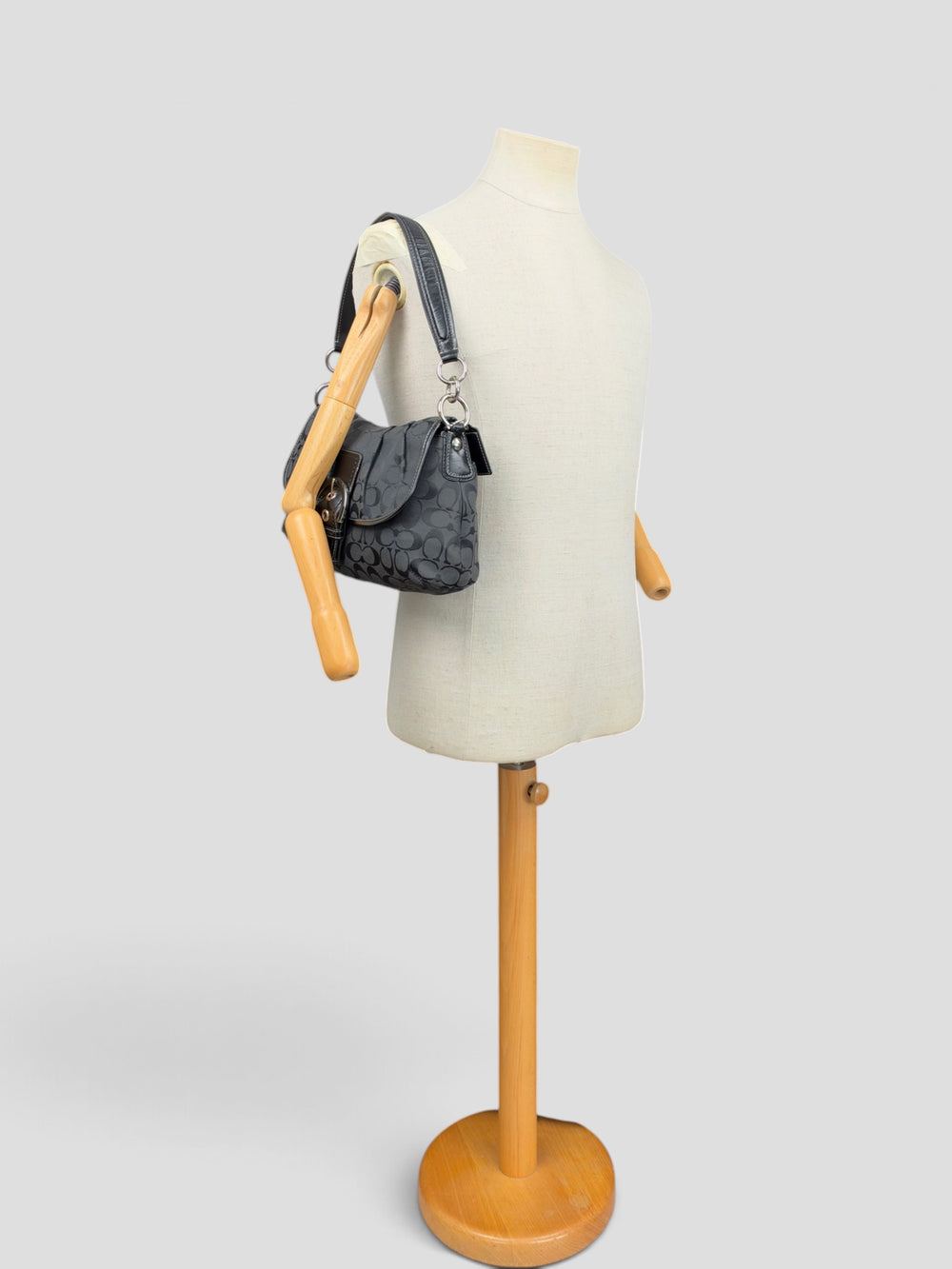 Coach Signature Soho Flap Baguette Shoulder Bag in Schwarz/Anthrazit, getragen an der Schneiderpuppe