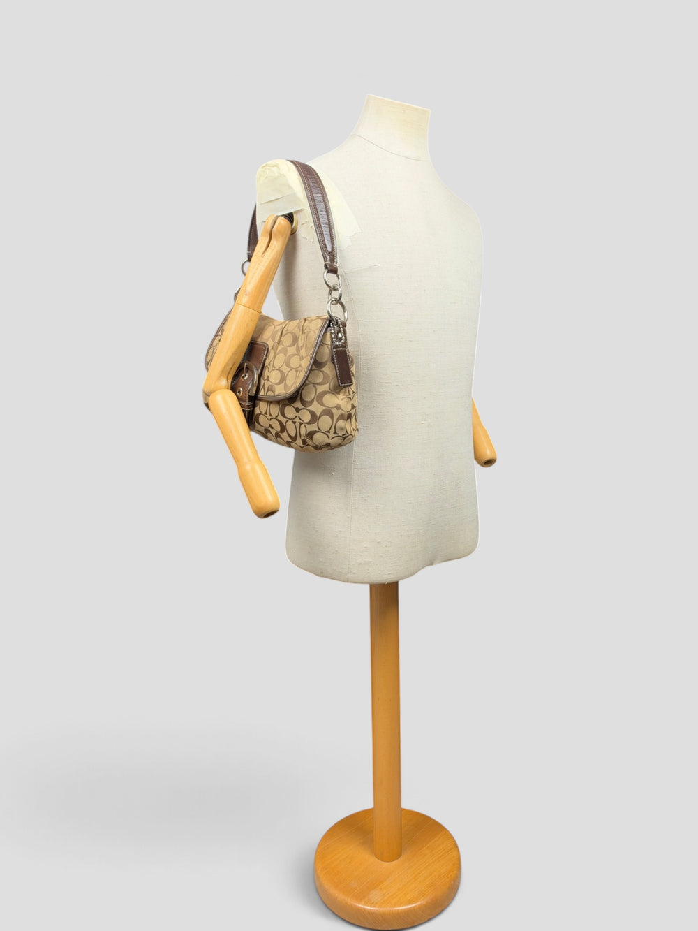 Coach Soho Signature Pleated Buckle Flap Baguette Shoulder Bag in Khaki/Braun, getragen an der Schneiderpuppe